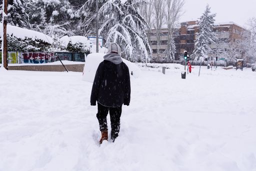 Young couple walking on a city street during heavy snow storm. Climate change, extreme weather. Storm Filomena in Madrid. Arturo Soria area