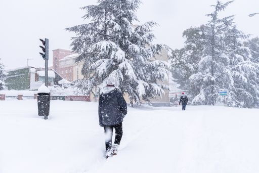 People walking on city highway covered in snow during heavy snowfall. Storm Filomena in Madrid. Arturo Soria residential area.