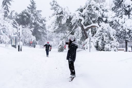 Young couple walking on a city street during heavy snow storm. Climate change, extreme weather. Storm Filomena in Madrid. Arturo Soria area
