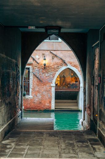 A vertical shot of an arch near the canal in Venice, Italy