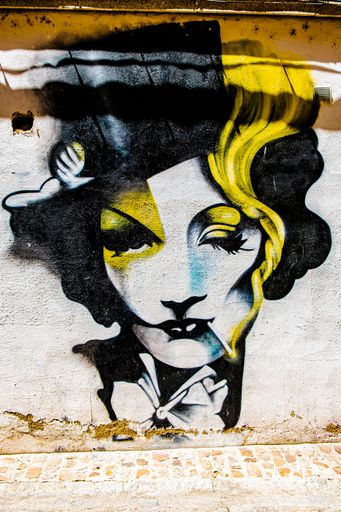 A vertical shot of a black and yellow street art of Marlene Dietrich on the wall in Zamora, Spain