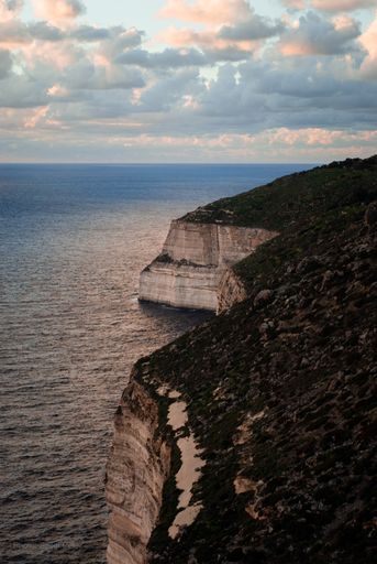 A vertical shot of a seascape under the cloudy skies during the day