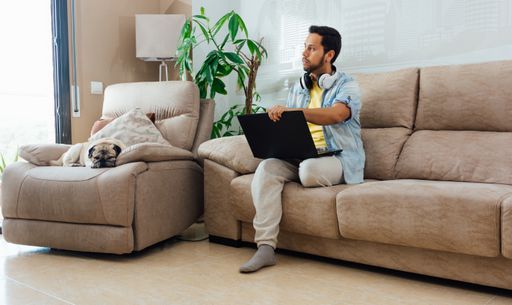 A young man with headphones using a laptop to work from home