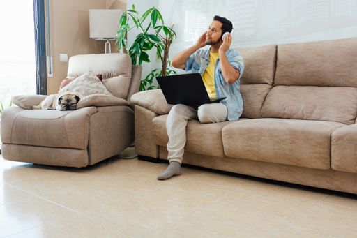 A young man listening to music with headphones and using a laptop to work from home