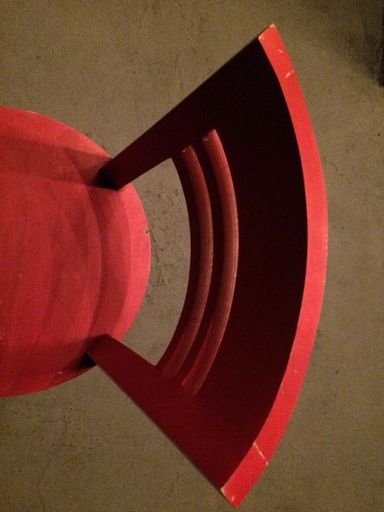 A vertical overhead shot of a red chair on a brown carpet