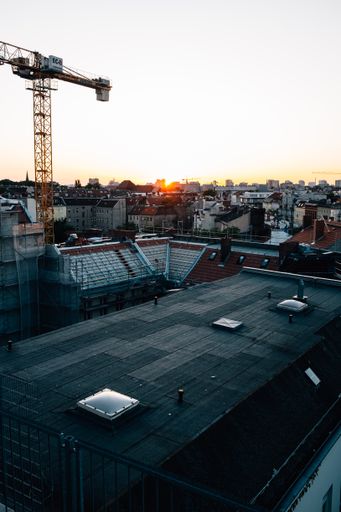 A vertical shot of many of buildings from the top in time of sunset with industrial work tower