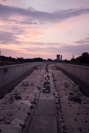 A vertical shot of purple sunset over a large cement pathway lined with flowers