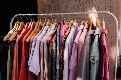 A closeup shot of colorful fashionable clothes hanging on a rail outside a shop