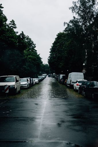 A view of cars parked on both sides of the road on a rainy day