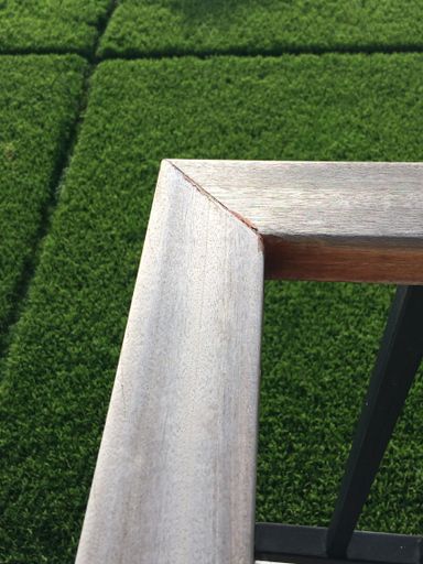 A vertical shot of a wooden surface with a blurred grassy field in the background