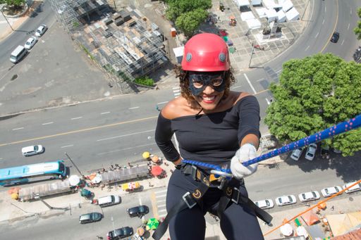 A high angle closeup of a woman walking down a tall Rappel building with a helmet