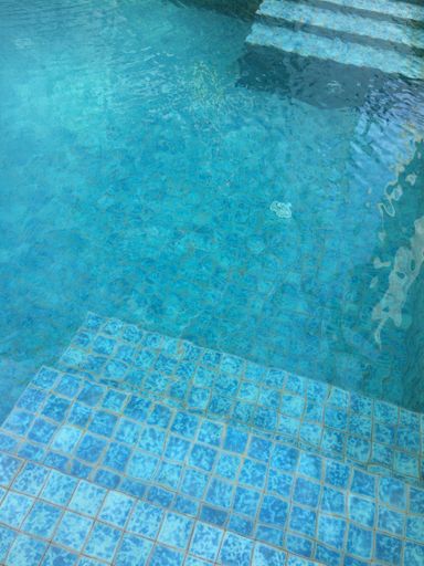 A vertical shot of stairs in the pool with a clear water