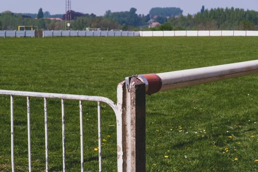 A closeup shot of a metal fencing on a green field background
