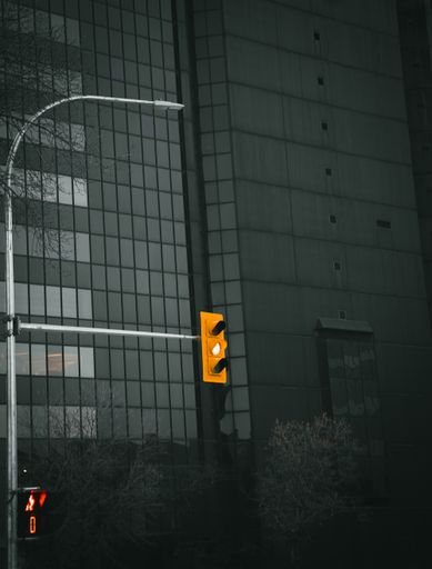 A vertical shot of traffic lights with a yellow light on it in grayscale