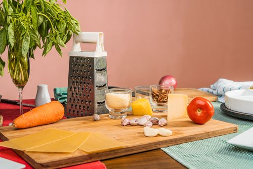 A close-up shot of different utensils and some raw ingredients ready for lasagna preparation on a table