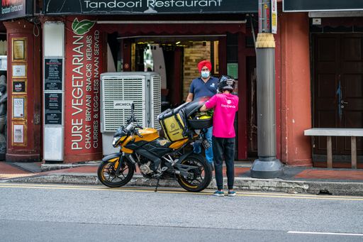 Rider from Food delivery service foodpanda outside  restaurant in Little India . Horizontal shot