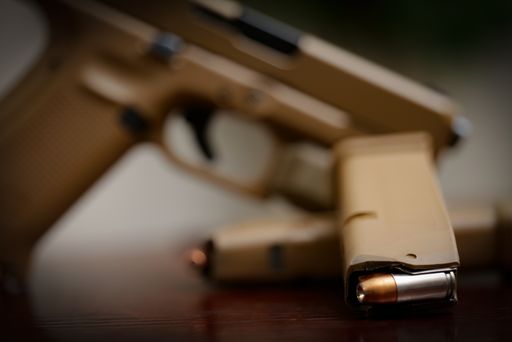A military tan handgun with a hollow point bullet seen in the magazine.