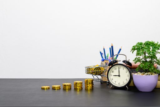 A stack of gold coins with office supplies on a desk - financial growth concept