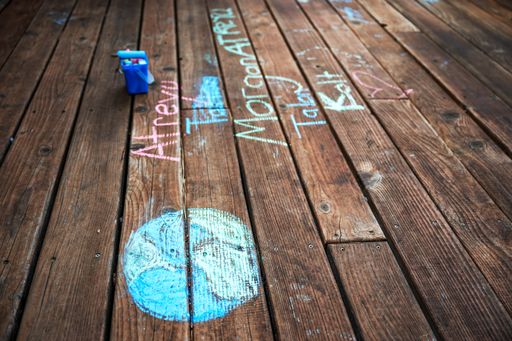 A view of a child's drawing of the planet earth with a chalk on a wooden surface during the quarantine