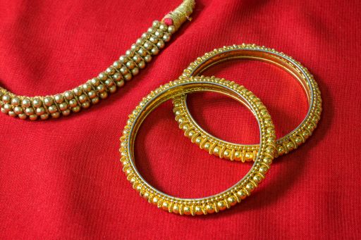 Two golden rings and a necklace on red background