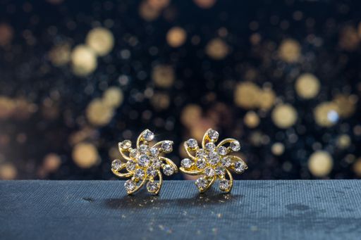 The golden diamond earrings with bokeh lights on the background
