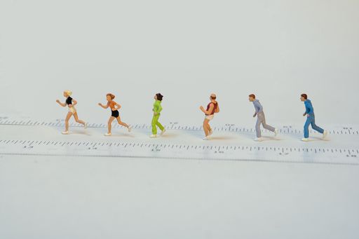 A group of miniature joggers in a row while walking past a meter - white background, copy space