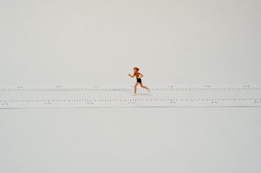 A miniature jogger while running next to a tape measure - white background, copy space