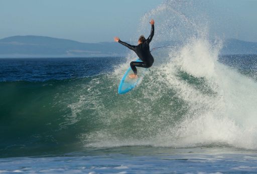 A scenic shot of a person surfing through the waves of the ocean on a sunny day