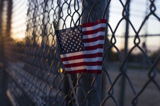 A closeup shot of the flag of the USA on a grid fence