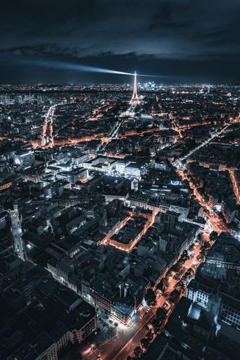 An aerial view of an Eiffel tower and dense buildings with illuminated lights at night