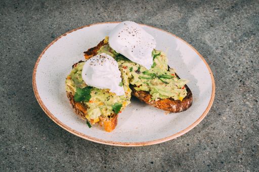 A closeup shot of a gourmet sandwich with guacamole and burrata