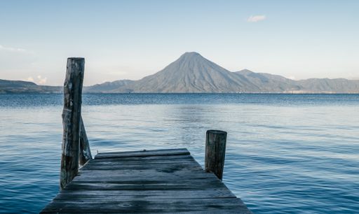 A closeup of an old wooden bridge over the Atitlan lake with a view of the mountains