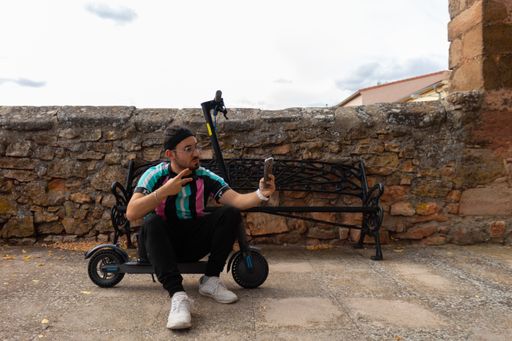 A smiling man talking on a video call with a cell phone sitting in his electric scooter