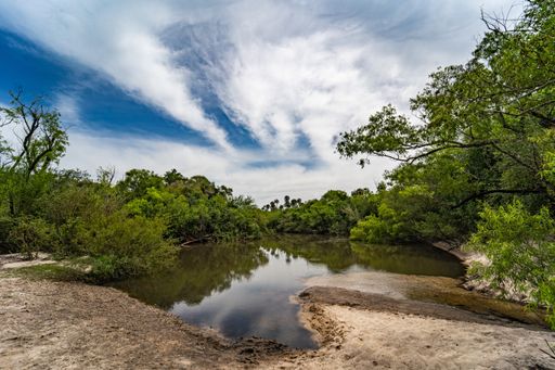 A beautiful shot of a lake surrounded by some trees under the cloudy skie