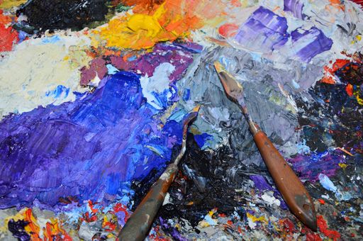 A beautiful high angle shot of the drawing tools on a colorful oil painting