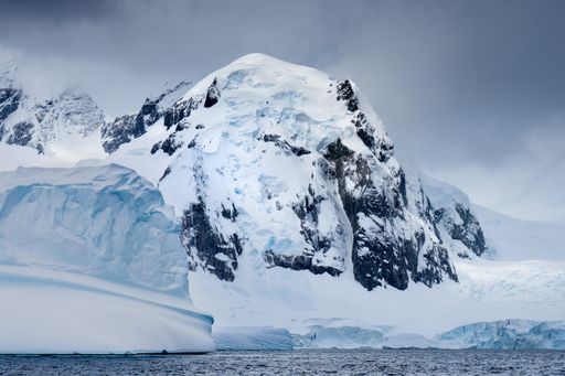 A landscape of icebergs in the ocean under a cloudy sky in Antarctica