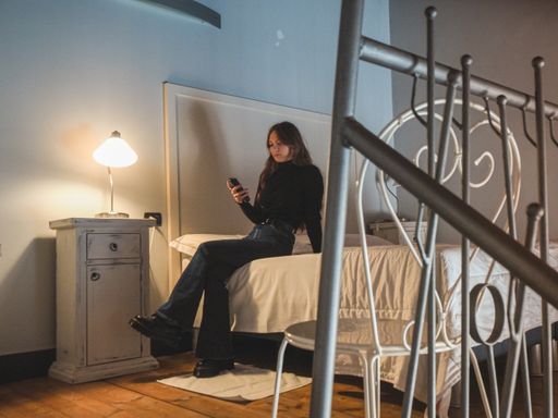 A closeup shot of a woman in the bedroom with a beautiful wooden interior, watching a TV