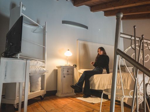 A closeup shot of a woman in the bedroom with a beautiful wooden interior, watching a TV