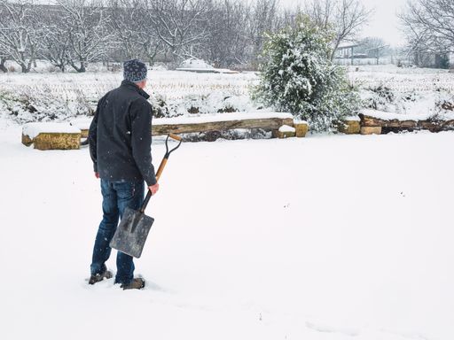 A Hispanic man with a shovel in hand to remove snow from the trail after a snowstorm in winter