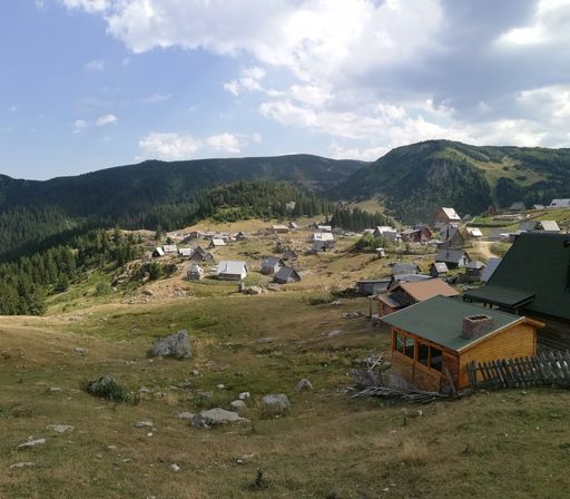 A village with small houses on the background of mountain forests under a cloudy sky
