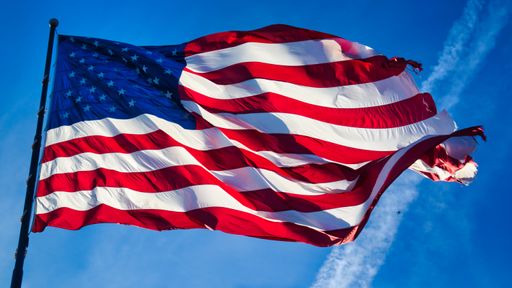 A low angle shot of the US flag waving in the sky