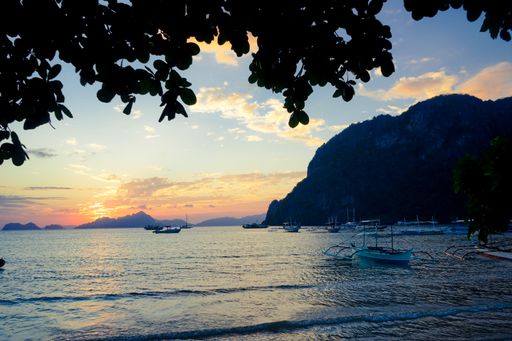 A beautiful shot of a sea with boats and a mountain in the distance under a blue sky