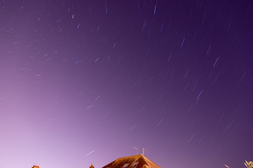 A low angle shot of Star trail above a house in Weymouth, Dorset