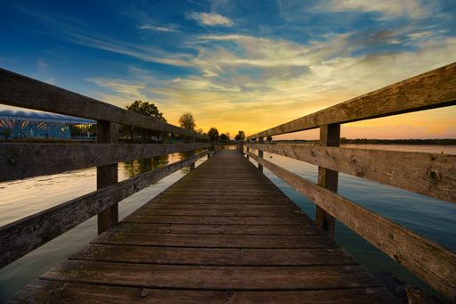 A wooden dock on the lake during the sunset