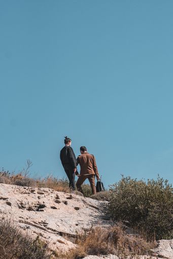 A vertical shot of a couple going down the hill under the clear skies