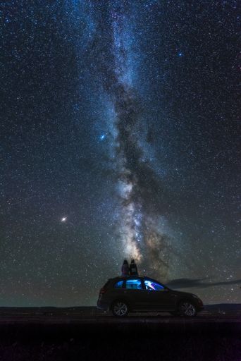 A vertical shot of the scenic view of the car under the starry night sky