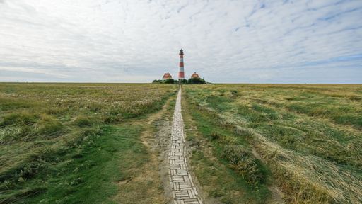 A narrow walkway leading to the Lighthouse Westerhever near St. Peter Ording at the Northern Sea, Baltic Sea, the Wadden Sea, Germany