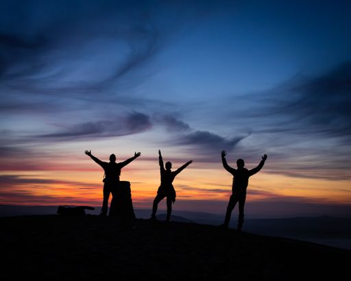 A silhouette of mountain climbers with the sunset background
