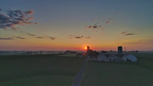 A breathtaking sunset in the countryside with a cloudy sky and rural houses on a background