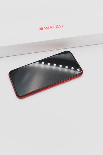 closed Apple watch product red box and iphone on a white tabletop with text space